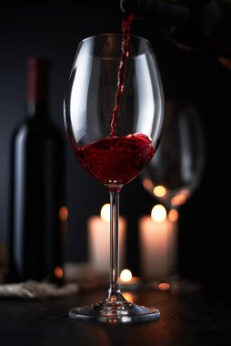 Kırmızı şarabı koyu arkaplanda şarap bardağına döküyorum..