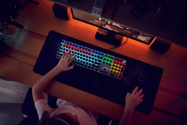 在玩在线视频游戏的同时 手拉手 向玩家展示推送键盘按钮的游戏 键盘引导灯 房间是暗的 图库图片