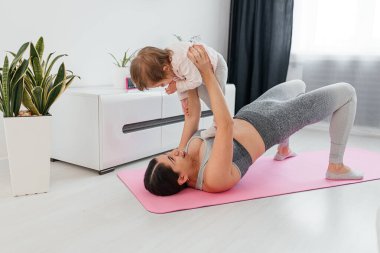 Mother and baby taking a break from working out. New mom bonding with her baby during her post-natal fitness routine