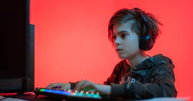 Bilgisayar oyunları, oyun yeri, genç oyuncu kulaklıkla bilgisayar oyunları oynuyor.