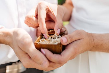 Alyanslı kadın ve erkek resmi. Genç evli çift el ele tutuşuyor, düğün günü. Alyanslı yeni evli çiftlerin elleri