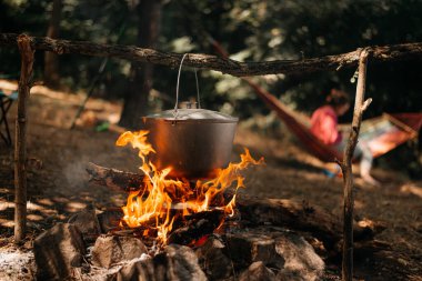 Kamp ateşi üzerinde bir tencerede pişirme