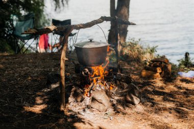 Kamp ateşi üzerinde bir tencerede pişirme.