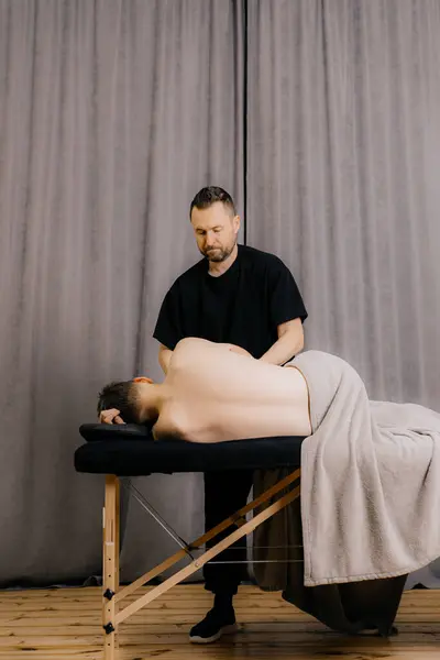 image of physiotherapist massaging man in hospital.