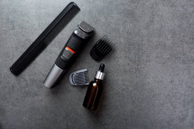 İnsan sakalı taş bir masa yüzeyinde, tarak, yağ ve elektrik budama makinesinde eşyalar yetiştiriyor..