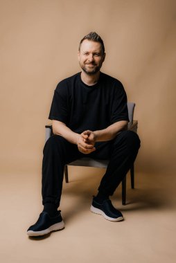 Bej arka planda duran gülümseyen olgun bir adamın portresi