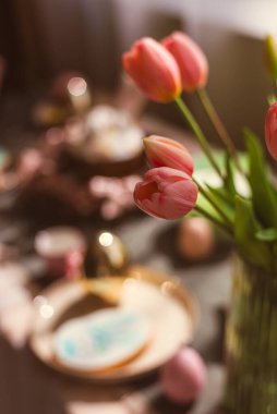 Sepette renkli yumurtaların ve mutfak masasında kırsal tarzda bir tavşanın Paskalya süslemesi. Bir kır evinin şenlikli iç mekanı.