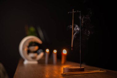 Tütsü çubuğu, karanlık arka plandaki ahşap bir stantta sigara içer. Aromaterapi, tütsü yakarken duman. Dualar ve meditasyon için duman. Buda 'ya dua et. Rahatlama ve yoga için tütsü.