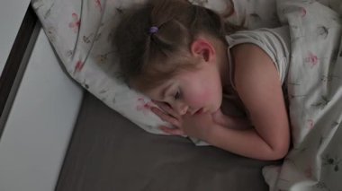 Küçük kız gece lambasıyla yatak odasında uyuyor. Geceleri çocuk şekerleme yapıyor.