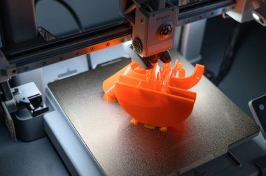 3D yazıcı baskı yatağında karmaşık turuncu bir model oluşturur. Yakın plan tasarım ve katkı maddesi üretimi odaklı hassas mühendislik ve teknolojiyi iş başında yakalar.