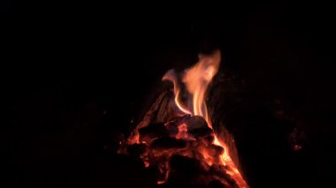 Parıldayan ateş ışığı, gece karanlığında parıldayan közleri ustalıkla aydınlatır.