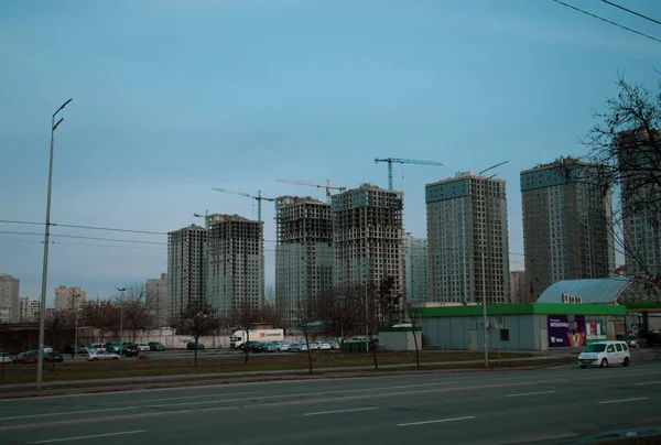 ウクライナのキエフ 2022年1月8日灰色の空に対する現代的な高層住宅マルチストーリーアパートの建物 建設クレーン 都市景観都市景観建設現場の近代建築 シティストリート — ストック写真