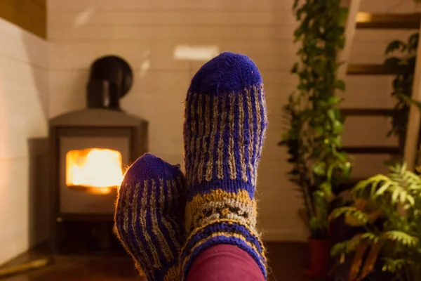 ニットウールの青い靴下の足 自宅で暖炉でリラックス 冬の寒い季節にコテージで暖まる人 無料時間 田舎の家で秋の夜に屋内レジャー — ストック写真