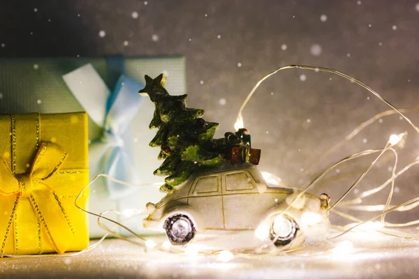 暗い銀の背景に導かれたガーランドライトの間で屋根 青と黄色のギフトボックス上のクリスマスツリーとおもちゃのレトロな車 2023年大晦日 冬の販売 ショッピングコンセプト 冬休み マジック — ストック写真