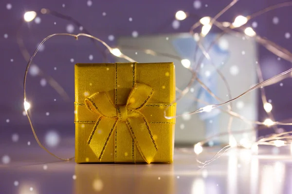 Led電球に囲まれた紫色の背景に弓で飾られた紙に包まれたギフトボックス ギフト 雪の結晶 お祭りの冬の休日の背景 2023年クリスマス — ストック写真