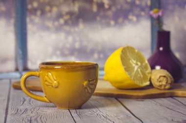 Limonlu zencefilli çay hala hayat. Ahşap masanın üzerinde arkasında kar yağan bir pencereye karşı hardal sarısı bir fincan. Sıcak bir sonbahar içeceğiyle sıcak bir kompozisyon, C vitamini ile içecek sağlıklı bir içecek..