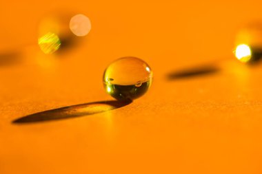 Sarı vitaminler, balık yağı hapları, omega 3 jelatin kapsülleri, yuvarlak tabletler turuncu masanın üzerine uzanıp zıt gölgeler bırakıyor. Tıbbi, sağlık, ilaç tedavisi. Tek renkli arkaplan üst görünümü