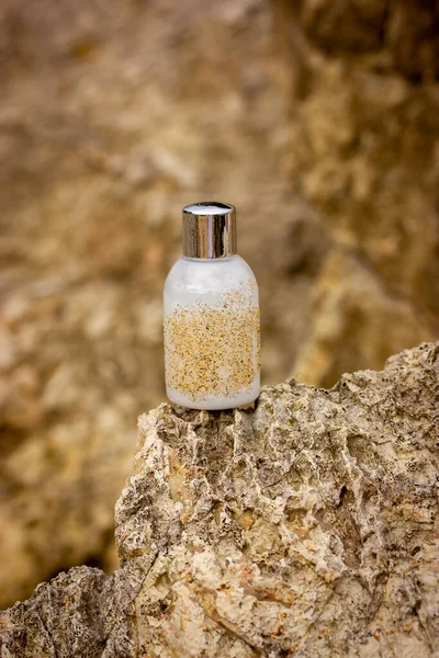 Cosmetics bottle with white natural skin hair care product - soap, shampoo, gel, serum on vertical brown beige rocks background, stone podium. Eco organic cosmetic tube modern still life. Body care.