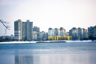 Kış göleti, göl, büyük bir şehirde nehir. Karla kaplı kıyılar ve uzaktaki yüksek binalar. Şehir manzarası, Aralık ayında bir metropol. Kışları Ukrayna 'da Kyiv. Soğuk hava.