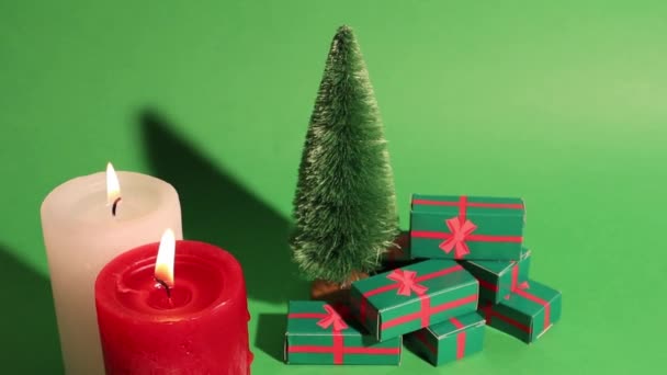 装飾的な松の木と緑のクリスマスレトロなビデオ 冬の休日のプレゼント付きのギフトボックス 赤い白い燃えるろうそくのろうそくの光 2023年大晦日 お祝いのコンセプト販売 — ストック動画