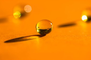 Sarı vitaminler, balık yağı hapları, omega 3 jelatin kapsülleri, yuvarlak tabletler turuncu masanın üzerine uzanıp zıt gölgeler bırakıyor. Tıbbi, sağlık, ilaç tedavisi. Tek renkli arkaplan üst görünümü
