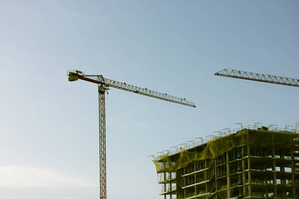 Construction of a residential high-rise multistory modern house building in a metropolis city. Construction cranes on horizon. Buildings under construction against sky. Housing business. New flats home