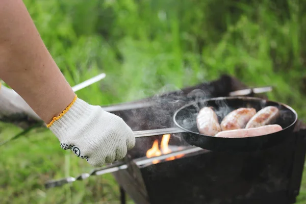 緑の公園 夏の森の中でキャンプファイヤーを調理します 肉ソーセージ ワイナーは石炭のバーベキューでグリッドドルで焼きます ピクニックで料理をする 煙と風味豊かな食べ物 — ストック写真