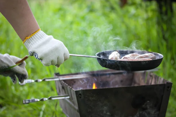 緑の公園 夏の森の中でキャンプファイヤーを調理します 肉ソーセージ ワイナーは石炭のバーベキューでグリッドドルで焼きます ピクニックで料理をする 煙と風味豊かな食べ物 — ストック写真