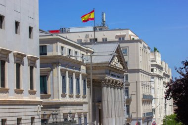 Madrid, İspanya - 1 Ağustos 2022 İspanya başkentinin tarihi merkezi. Avrupa şehrinin hükümet binasında eski bir mimari. İspanyol bayrağı olan bir evin çatısının ön cephesi. 