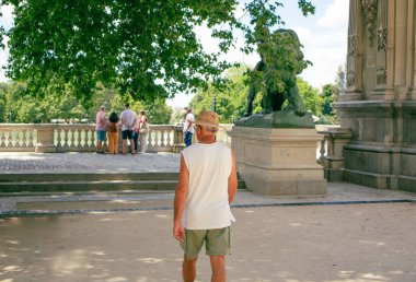 Madrid, İspanya. 2 Haziran 2022. Turist, yeşil yaz parkında şapkalı yalnız gezgin. Etiro Parkı 'nın eski Avrupa mimarisi. Sokakta yürüyen insanlar. Dünyayı dolaşmak..