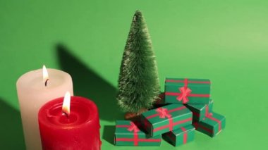 Dekoratif çam ağacının olduğu yeşil Noel retro videosu, kış tatilinde hediye kutuları. Kırmızı beyaz yanan mumlar mum ışığı. Yeni yılın kutlu olsun 2023. Kutlama konsepti, satışlar