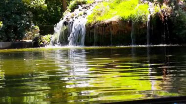 Artificial waterfall rapids, water flowing downstream in spring, summer nature reserve, park, garden. Green-yellow water in a body of water, a reservoir. Nature, ecology, tranquility, harmony concept.