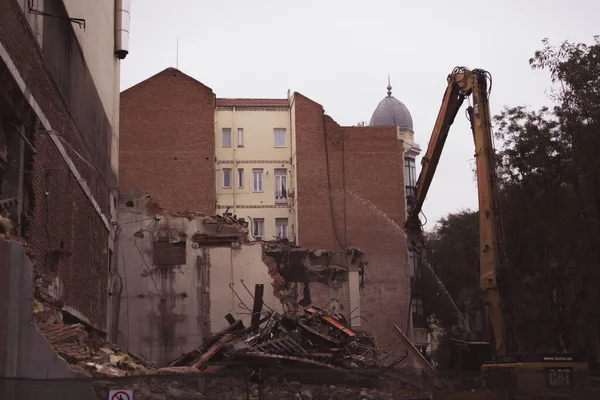 スペインのマドリード 2022年11月24日市内の歴史地区にある古いレンガ造りの住宅ビルの解体 都市空間上のクローラー掘削機 古いヴィンテージの家の破壊 土石流 — ストック写真