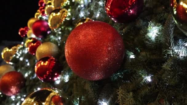 鮮やかな赤 金の黄色のボールとLedガーランドで飾られた輝くクリスマスツリーをきらびやかに 大晦日のための休日の装飾2023 クリスマスの装飾 おもちゃのお祭りの背景 スローモーション — ストック動画