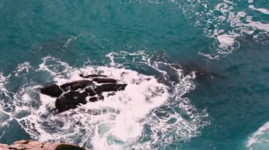 Yazın Atlantik Okyanusu 'nda mavi dalgalar kayalıklara kırılarak beyaz köpük oluşturur.