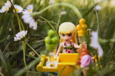 Madrid, İspanya. 1 Mayıs 2022. Oyuncak sarışın LEGO, parktaki yemek alanından dondurma satıyor. Elinde dondurma külahı tutan bir kadın yüksek otların yeşil çimlerinde duruyor yaz tatillerinde beyaz papatyalar..