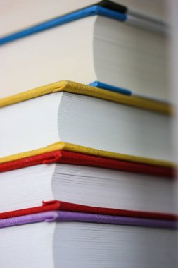 A stack of modern red, yellow, blue, violet books in bright hardcovers stacked on a bookshelf. Reading literature, hobby, knowledge, studying, science concept. Back to School 2022. Printbooks. 