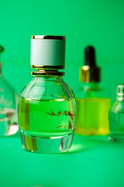 Cam bir şişe Eau de Tuvalet parfümü, yeşil kokular dikey arka planda. Şişeler için kozmetik şart. Kadın güzellik konsepti. Parfüm için birkaç şişe. Kadınlar için kokular. 