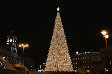 Madrid, İspanya. 1 Aralık 2022 Çok güzel dekore edilmiş Noel ağacı Bir sürü çelenk, parlayan ışıklar, Gece şehrinin arka planında bir Noel yıldızı. Sol Meydanı. Kış tatilini kutluyoruz.