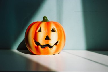 Süslü seramik parlak turuncu balkabağı. Komik Jack o fener kabak feneri mavi duvara karşı zıt gölgeler. Cadılar Bayramı için rahat bir ev dekorasyonu. 31 Ekim partisi.