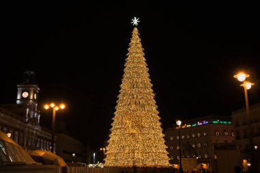 Madrid, İspanya. 1 Aralık 2022 Çok güzel dekore edilmiş Noel ağacı Bir sürü çelenk, parlayan ışıklar, Gece şehrinin arka planında bir Noel yıldızı. Sol Meydanı. Kış tatilini kutluyoruz.