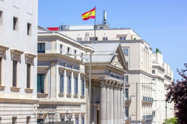 Madrid, İspanya. 1 Ağustos 2022 İspanya başkentinin tarihi merkezi. Avrupa şehrinin hükümet binasında eski bir mimari. İspanyol bayrağı olan bir evin çatısının ön cephesi. 