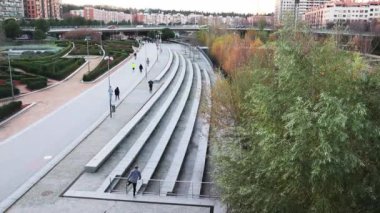 Madrid, Spain. December 1, 2022 Street in city park, promenade. People walking, exercising, running outside during a day. Urban space, cityscape with green zones. Madrid Rio Manzanares aerial view.