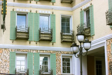 Kyiv, Ukrayna. 1 Mayıs 2021 Tarihi, dış bina olarak korunmuş çok katlı konforlu bir ev restore etti. Birçok pencerenin sarı bej ön cephesi, yeşil ahşap panjurlar. Klasik mimari detayları. Retro fener