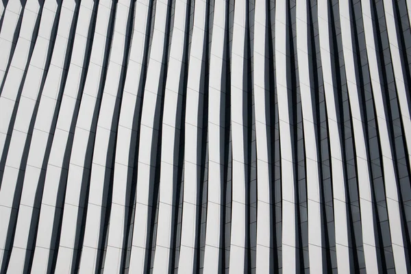 Lines in architecture. Modern office facade. Fragment of tall blue building with contrast shadows. Abstract built structure background. Business quarter in a modern city. Urban scene pattern, texture.