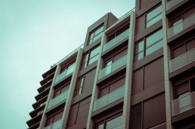 Modern çok katlı bir apartmanın gri mavi cephesi, aşağıdan yukarıya ev manzarası. Dış mekanın ev detayları, bir metropolün mimarisi. İnşaat, gayrimenkul yatırım kavramı. 