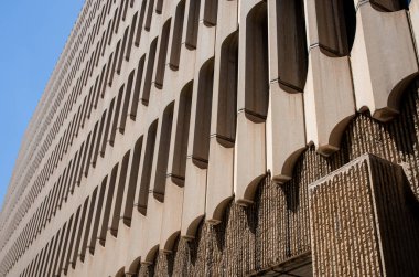 Modern architecture in the style of brutalism. Fragment of a concrete building looking up from below into perspective against a blue sky. New Brutalism is a branch of postwar architectural modernism. 
