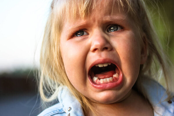 Unhappy child crying loudly with mouth open because of his parents' divorce. Real negative emotions. Bullying, child abuse, child protection. Misery, grief concept. Child of war bereft of parents. 