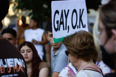 Madrid, Spain July 24, 2022 An elderly woman with a placard reading Gay Ok walks in a pride month parade. Crowd of people supporting equality, freedom of choice of sexual orientation. Equality concept