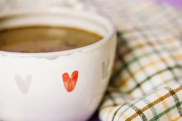 White hand-painted ceramic cup with symbols of love. Red grey hearts painted on a mug. Hot coffee, cappuccino cocoa, espresso, hot chocolate drink. Cozy still life, tableware details on rustic kitchen